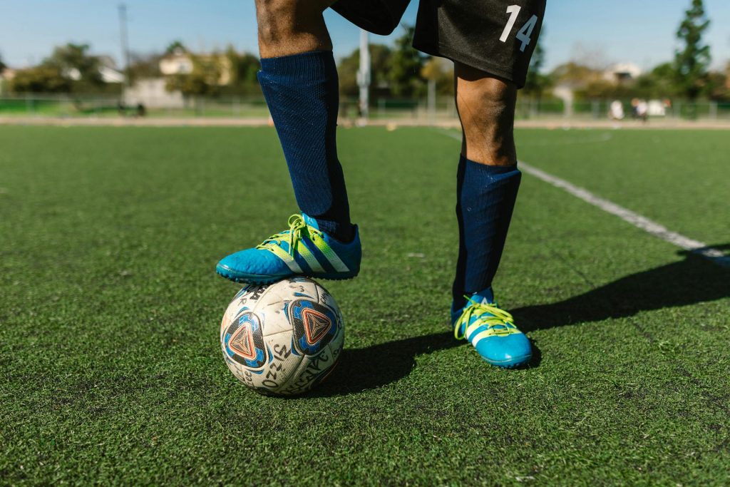 A person on a soccer field with a soccer ball, illustrating metatarsalgia, or pain in the ball of the foot. Metatarsalgia is a general term used to describe pain and inflammation in the forefoot.